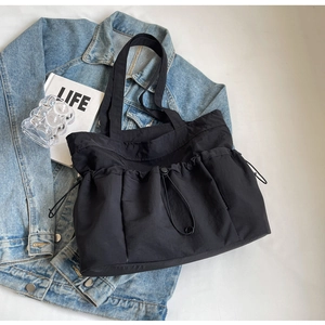 Detail of black nylon tote bag with three functional drawstring pockets and wide strap