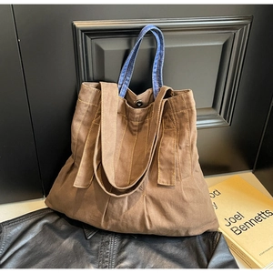Detail of retro brown canvas tote bag with blue denim handles and metal snap button