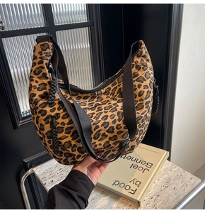 Detail of leopard print crescent bag with woven zipper pulls on marble table