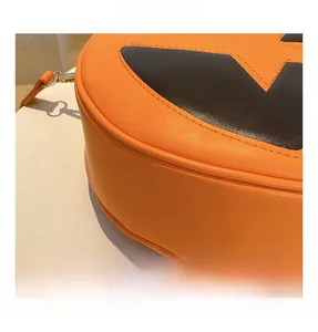 Detail of bright orange pumpkin bag showing soft PU leather texture and black accents