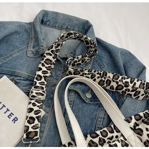 Detail of leopard print canvas strap with silver metal buckle on a casual tote bag