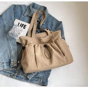 Close-up of khaki pleated tote bag with drawstring detail on a lifestyle background