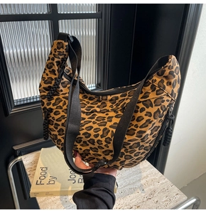 Detail of leopard print canvas crescent bag with black wide strap and cord zipper pull