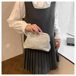Detail of a chic cream fabric clutch bag featuring silver studs and metal frame closure