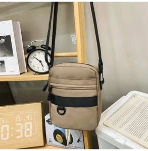Close-up of khaki crossbody bag featuring front zipper pocket and durable D-ring details