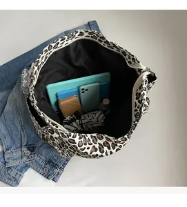 Interno spazioso della borsa tote in tela leopardata con vari oggetti quotidiani