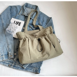 Detail view of khaki nylon tote bag with drawstring design and multiple pockets on desk