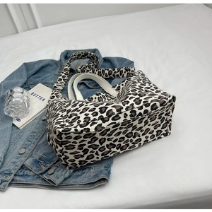Close-up of leopard print canvas tote bag with leather handles and denim jacket background