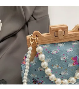 Detail of denim bag with sequin butterfly, wooden frame, and pearl bead handle