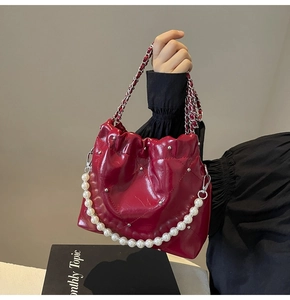 Detail of burgundy quilted leather bag with silver studs and elegant pearl handle strap
