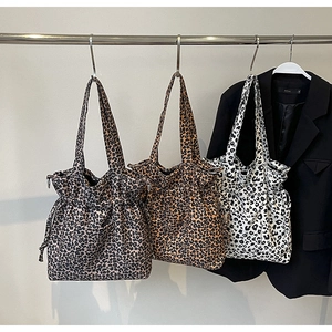 Detailed view of three leopard print canvas tote bags with drawstring and wide straps