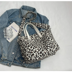 Detail shot of leopard print canvas tote bag with leather handles and wide crossbody strap