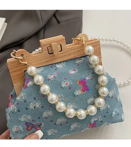 Detail of denim handbag with sequined butterfly embroidery and white pearl handle