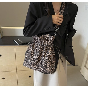 Detail of leopard print canvas bucket bag with drawstring closure and metal buckle strap