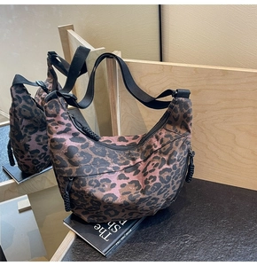 Detailed macro of leopard print canvas bag with durable black wide strap and woven zipper pull