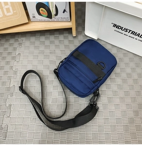 Detail of dark blue canvas messenger bag featuring multiple zippers and adjustable strap
