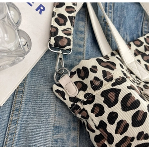 Detailed macro view of leopard print canvas tote bag with adjustable strap and silver hardware