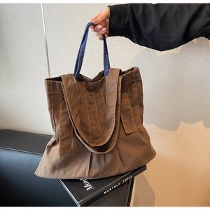 Detailed close-up of dark brown canvas tote bag featuring unique blue denim handles