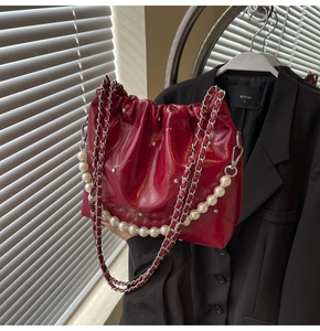 Detail of red quilted leather bucket bag with silver studs and faux pearl handle strap