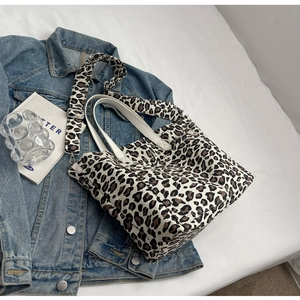 Detail view of leopard print canvas tote bag with adjustable strap on white background