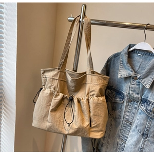 Detailed view of beige nylon tote bag with drawstring pleated pockets and thin shoulder straps