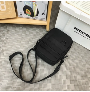Detail view of black functional crossbody bag with multiple compartments and tactical straps