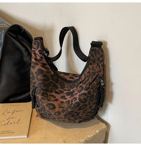 Detail view of leopard print canvas crescent bag with black zipper and woven strap