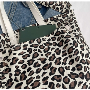 Macro view of leopard print canvas tote bag featuring a spacious front pocket for tablet