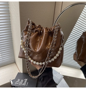 Detail of caramel glossy bucket bag with quilted patterns and elegant pearl chain handle