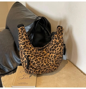 Detail of leopard print hobo bag with black wide strap and woven zipper puller