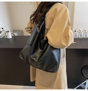 Vue latérale d'un grand sac cabas noir en cuir grainé porté à l'épaule pour le travail