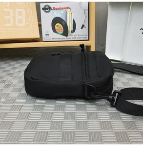 Detail of durable black nylon crossbody bag with reinforced webbing and plastic hooks