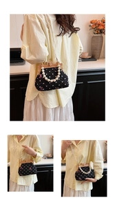 Detailed close-up of vintage black shell bag with floral butterfly embroidery and pearl strap