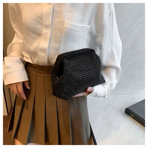 Close-up of elegant black rhinestone shell clutch held by model in formal outfit