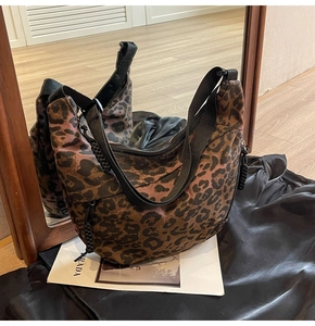 Detail of leopard print canvas hobo bag featuring a wide black textile shoulder strap
