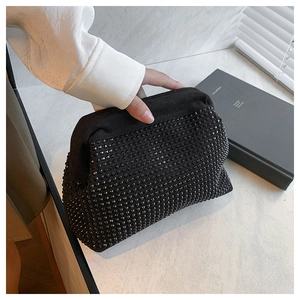 Close-up of a black rhinestone-studded clutch bag held by a person in a white shirt