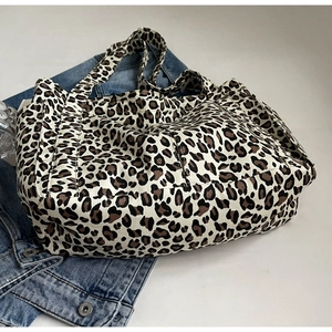 Dettaglio della borsa tote in tela leopardata con tasca laterale su sfondo denim blu
