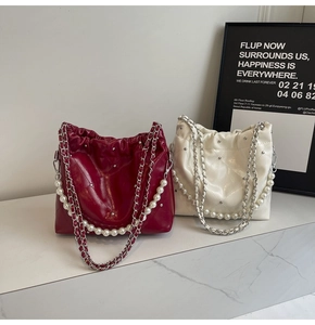 Close-up of quilted leather bucket bag with metallic rivets and pearl chain strap