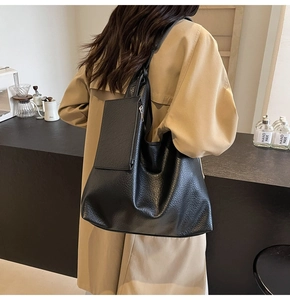 Détail du sac cabas noir avec texture litchi et petit sac à fermeture éclair assorti sur le côté