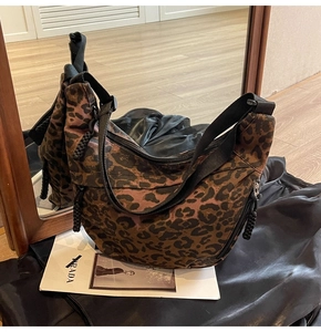Detail of leopard print canvas bag with adjustable shoulder strap and multiple zip pockets
