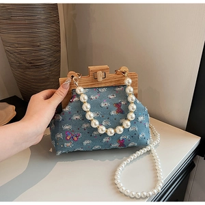 Detail of blue denim shell bag with sequined butterflies and white pearl handles
