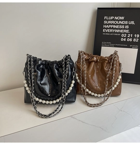 Close-up of quilted bucket bag with pearl chain strap and metal rivet details