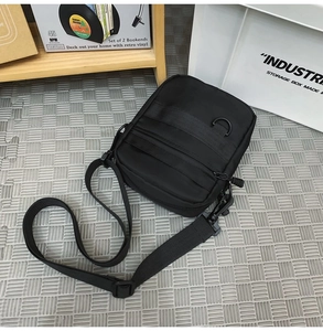 Detail view of black nylon messenger bag with multiple zipper pockets and adjustable strap