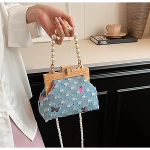 Detail of denim shell bag with sequin butterfly, wooden frame and pearl bead handle