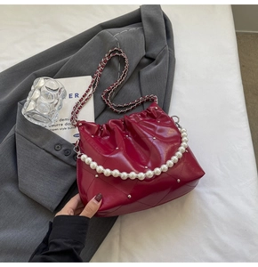 Close-up of deep red quilted hobo bag with large pearl handle and silver metal chain