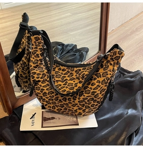 Detail of leopard print canvas crescent bag with adjustable strap and dual side zippers