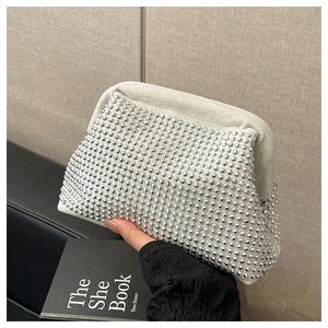 Close-up of white shell bag with shiny silver studs and elegant pleated cloud shape