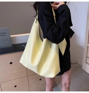 Détail de la texture cuir jaune du sac cabas porté à l'épaule par un mannequin