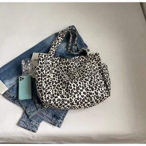 Dettaglio della borsa tote leopardata con tasche laterali su sfondo in denim casual