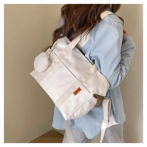 Close-up of off-white canvas tote bag with orange logo tag and mini round coin purse